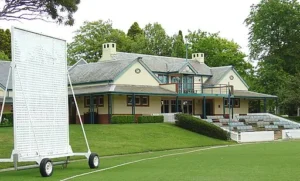 Bradman Oval in Bowral featuring a historic red brick pavilion clock tower and neatly maintained cricket field under a blue sky. The iconic sporting ground is a popular stop on a Bowral and Berrima family holiday exploring the Southern Highlands.