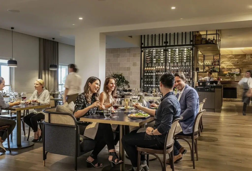 Modern dining space at Restaurant Botanica at Spicers Guesthouse with guests enjoying wine and seasonal dishes in a stylish light filled setting. The relaxed yet sophisticated restaurant is a popular choice for dining on a Hunter Valley family holiday.
