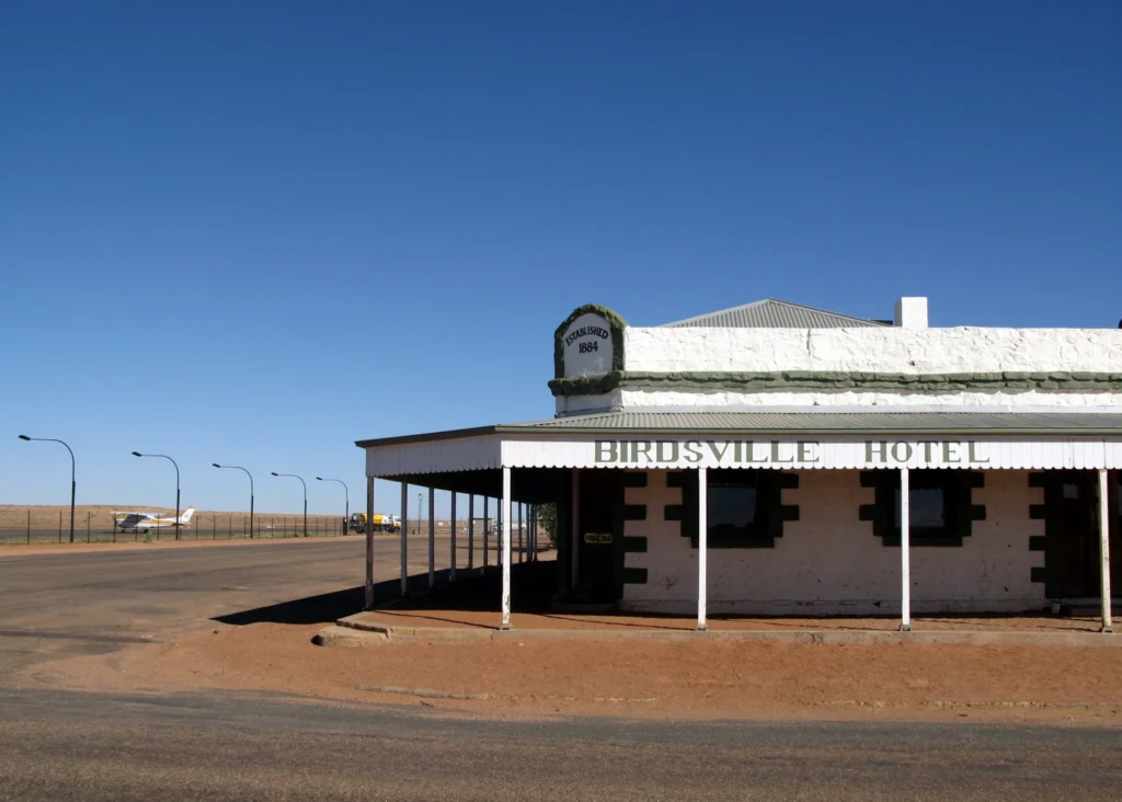 The historic Birdsville Hotel stands on a quiet outback street under a clear blue sky. The remote pub is a classic stop for families exploring an outback Queensland family holiday.
