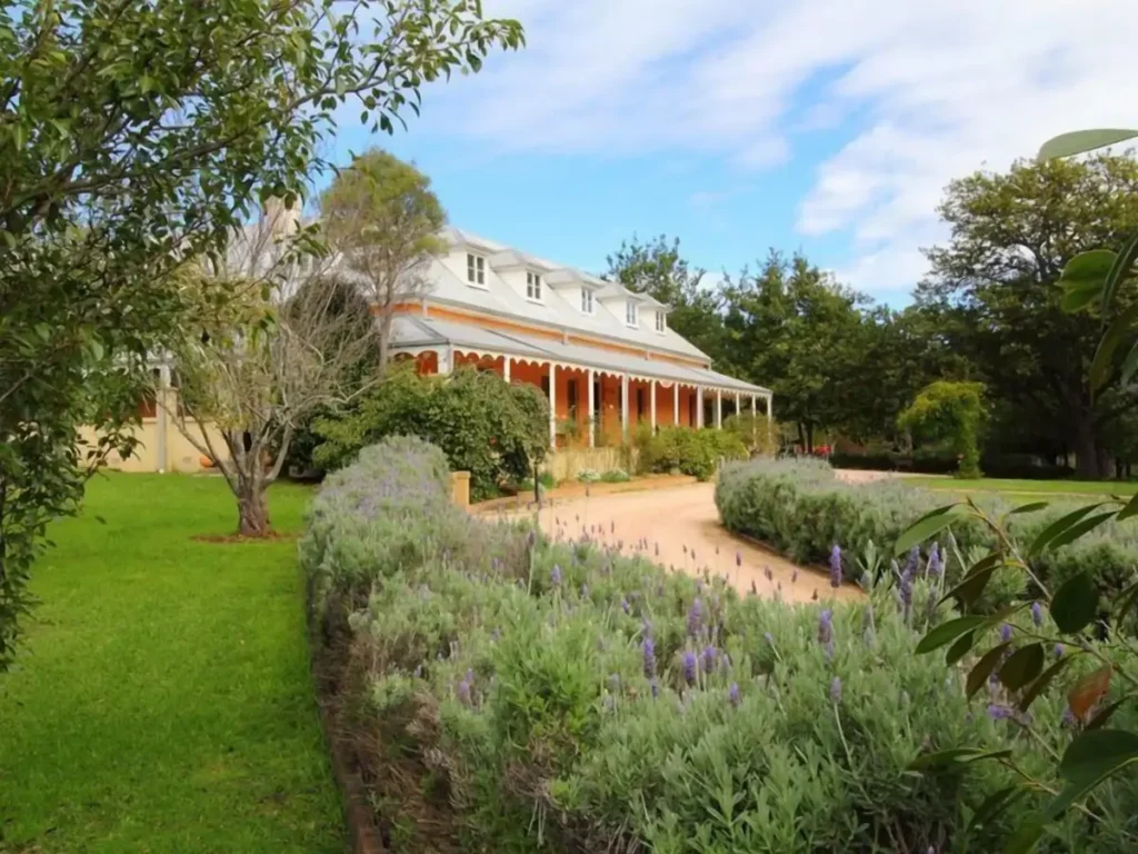 Fitzroy Inn in Bowral featuring a charming heritage style country house with a wraparound verandah and manicured cottage gardens lined with lavender. The peaceful Southern Highlands setting makes it a welcoming stay during a Bowral and Berrima family holiday.