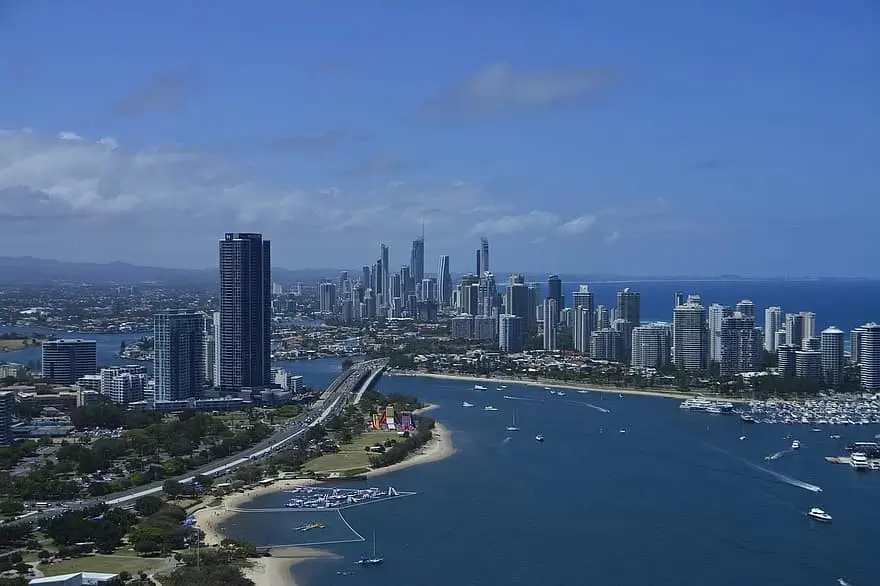 The Gold Coast skyline rises beside the Broadwater, with high rise buildings, marinas, beaches, and boats under a blue sky. This city and coastal view sets the starting point for a Gold Coast to Byron Bay family holiday.