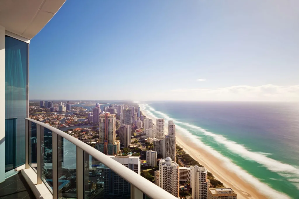 A balcony at Hilton Surfers overlooks the Gold Coast skyline, long sandy beach, and rolling ocean waves. The high rise coastal view makes a scenic city stay during a Gold Coast to Byron Bay family holiday.