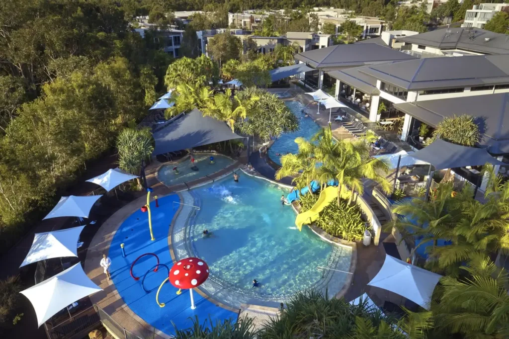 RACV Noosa has a large family pool with water slides, splash play features, shade sails, palm trees, and resort buildings around it. The kid friendly pool area makes a fun stop on a Great Beach Drive family holiday.