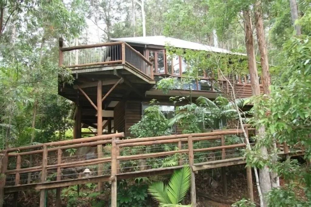 Secrets on the Lake is a timber treehouse style retreat surrounded by dense rainforest and connected by elevated wooden walkways. The secluded forest setting offers a peaceful stay during a Sunshine Coast Hinterland family holiday.