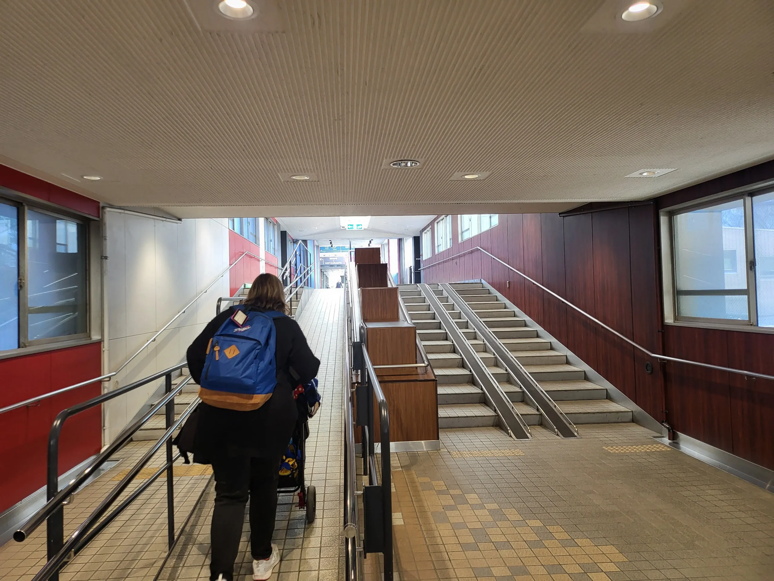 person pushing a pram up accessibility ramp beside stairs