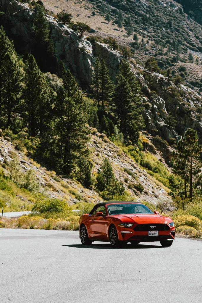 red-convertible-sports-car-parked-on-a-scenic-mountain-road-surrounded-by-lush-green-trees.