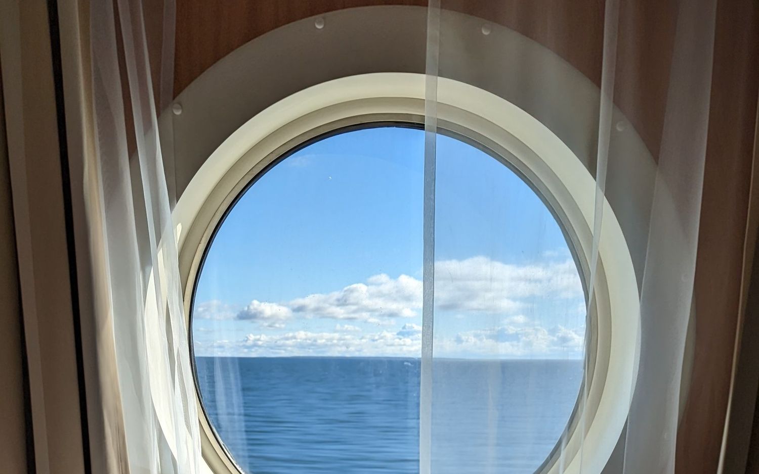 Cruise ship cabin with a porthole window looking out to sea