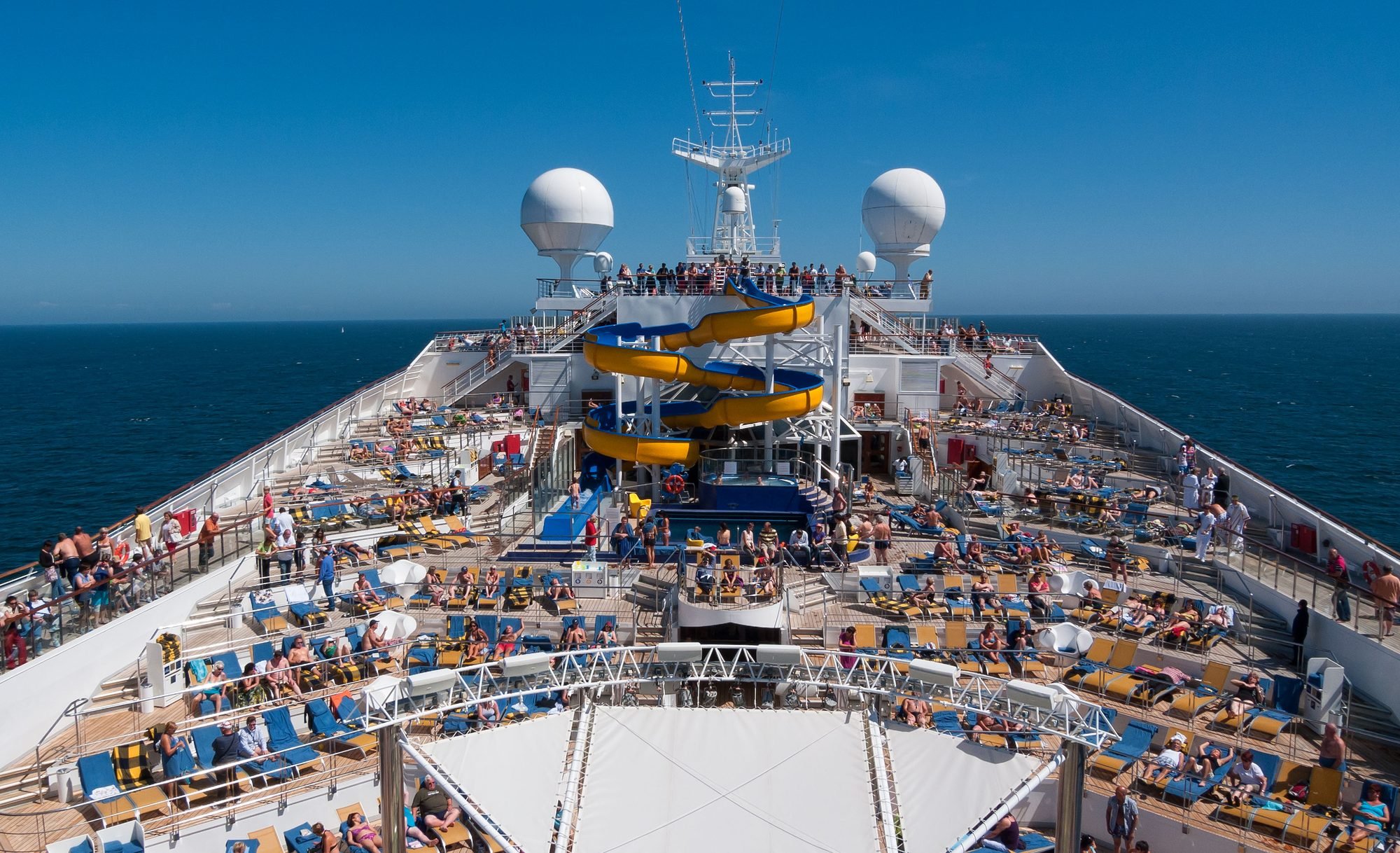 Spiral waterslide and pool deck on a large family cruise ship at sea